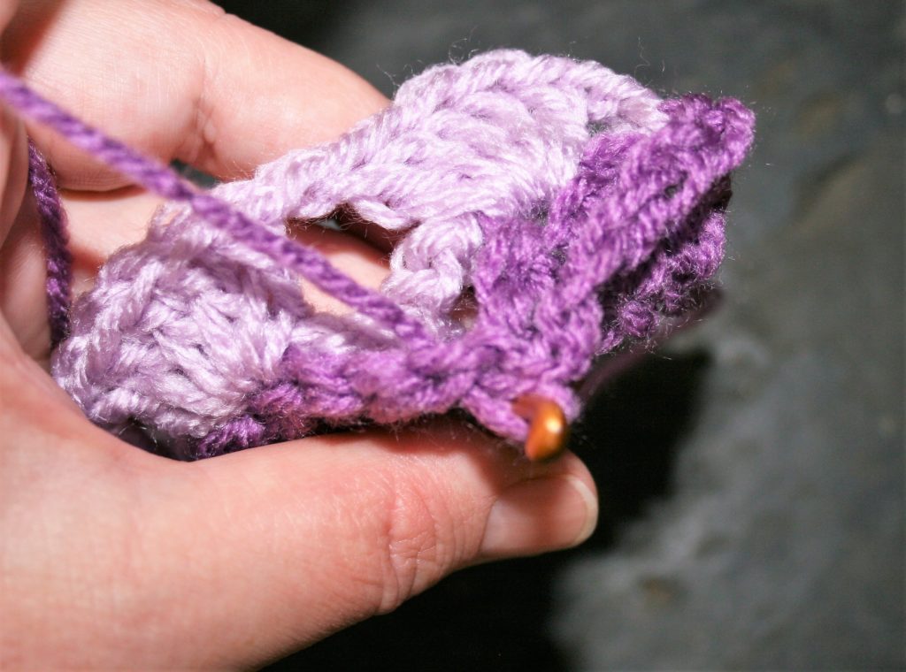 Single crochet in the chain 1 space between the double crochets of the same color